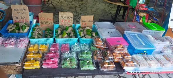 Kuih laid out in baskets with handwritten price signs